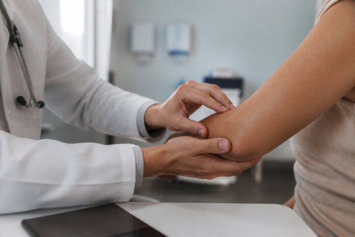 Mãos de médico residente em jaleco examinando paciente em consultório, fundo desfocado, sem rostos identificáveis