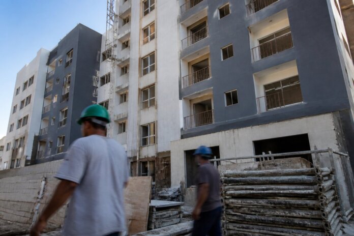 Fachada de edifício residencial em construção ou recém-finalizado, com estrutura de blocos de apartamentos, andaimes ou
