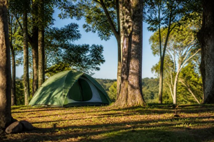 Barraca de camping entre árvores sob céu azul