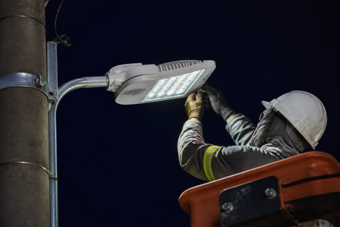 Técnico instala luminária em poste